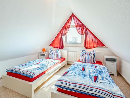 Schlafzimmer im Dachgeschoss mit 2 Betten und einem Fenster in der Unterkunft Reetdachhaus mit Sauna und Boddenblick - D 128.036 in Vieregge