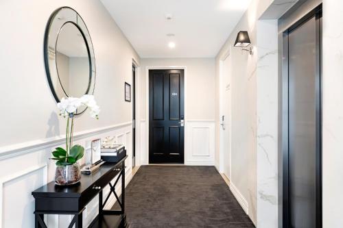 a hallway with a black door and a mirror at Manhattan Apartments - Glen Iris in Melbourne