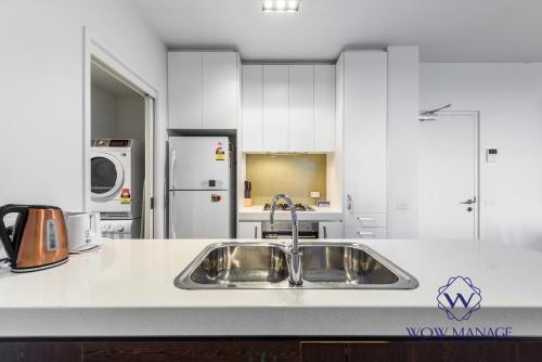 a kitchen with a stainless steel sink and white cabinets at WOW Apartment on Swanston in Melbourne
