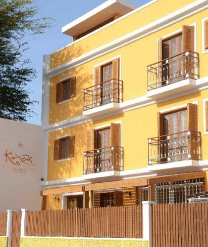 a yellow building with balconies and a fence in front of it at Kira's Boutique Hotel in Mindelo