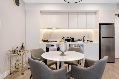 a kitchen with a table and chairs and a refrigerator at Manhattan Apartments - Glen Iris in Melbourne