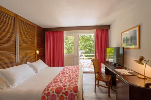 um quarto de hotel com uma cama, uma secretária e uma televisão em Hotel Ker Juliette em Pornichet