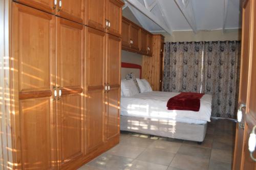 a small bedroom with a bed and wooden cabinets at Lake Sands Manor in Pietermaritzburg