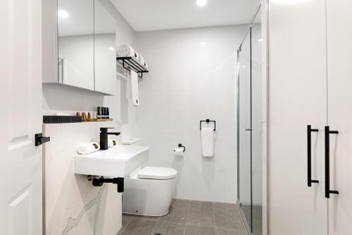 a white bathroom with a sink and a shower at Manhattan Apartments - Glen Iris in Melbourne