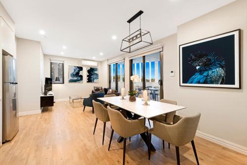 a dining room and living room with a table and chairs at Manhattan Apartments - Glen Iris in Melbourne