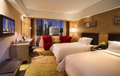 a hotel room with two beds and a desk at Grand Skylight Hotel Shenzhen (Huaqiang NorthBusiness Zone) in Shenzhen