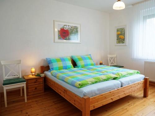 um quarto com uma cama com almofadas azuis e verdes em Ferienhaus Waldblick, 35209 em Hesel