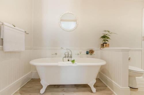 a white bathroom with a tub and a toilet at The Robberg Beach Lodge - Lion Roars Hotels & Lodges in Plettenberg Bay