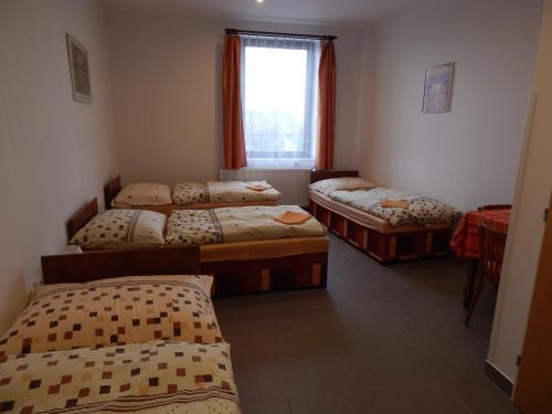 three beds in a room with a window at Penzion U Kašných in Mníšek pod Brdy