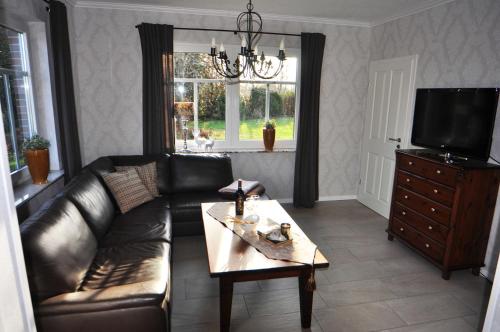 uma sala de estar com um sofá de couro e uma mesa de centro em Ferienhaus Adamla, 65319 em Moormerland