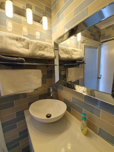 a bathroom with a sink and a mirror and towels at JUST-4-YOU! amazing sea views, WIFI, fullly air-conditioned, king bed in Vincentia