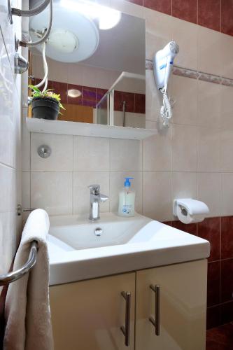 a bathroom with a white sink and a mirror at Pink House Apartments in Novalja