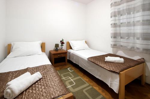 two beds in a small room with towels on them at Pink House Apartments in Novalja