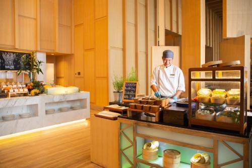 a chef standing in a kitchen preparing food at Avani Plus Riverside Bangkok Hotel in Bangkok