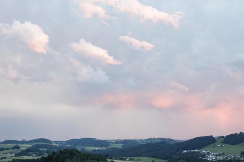 a cloudy sky with trees and houses in a field at Ferienwohnung im Mühlviertler Panorama Vierseithof in Lembach im Mühlkreis