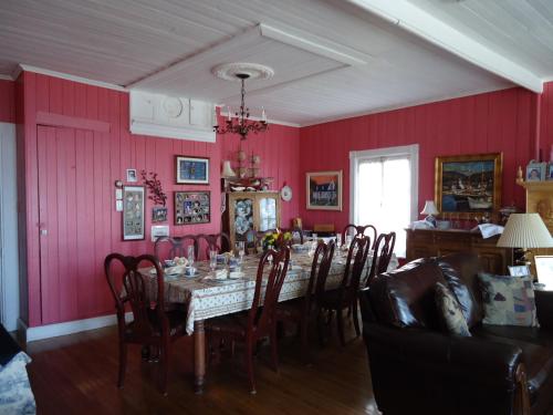 a dining room with red walls and a table and chairs at Maison Hovington in Tadoussac
