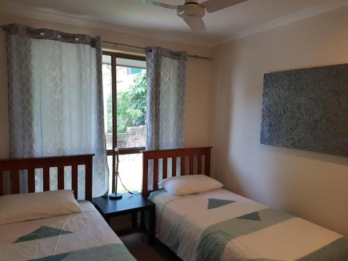 two beds in a room with a window at Coora 13 in Rainbow Beach