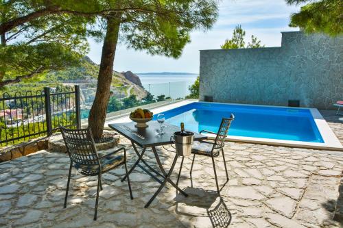 a patio with a table and chairs and a swimming pool at Villa Degenija - Principality of Zarijak in Jablanac