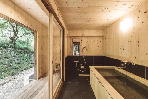 KosugeにあるNIPPONIA 小菅 源流の村の木製バスルーム(バスタブ付)、窓が備わります。