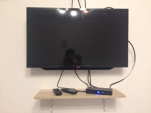 a flat screen tv on a stand with two remote controls at โฮมสเตย์ ยายหนั่น in Ban Nong Kham Tai