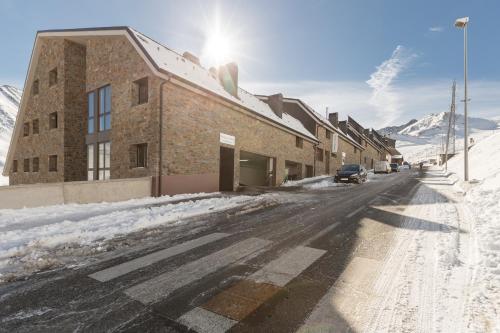 a building on a snowy street with mountains in the background at Pierre & Vacances Pas de la Casa Princesa in Pas de la Casa