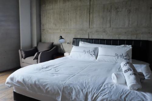 a bedroom with a white bed and a chair at CoffeeLoft in Taitung City
