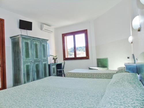 a bedroom with two beds and a green cabinet at Hotel Meridiana in Arbus