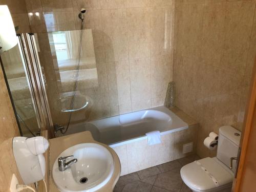 bagno con vasca, lavandino e servizi igienici di Apartamentos Pomba Branca a Olhos de Água