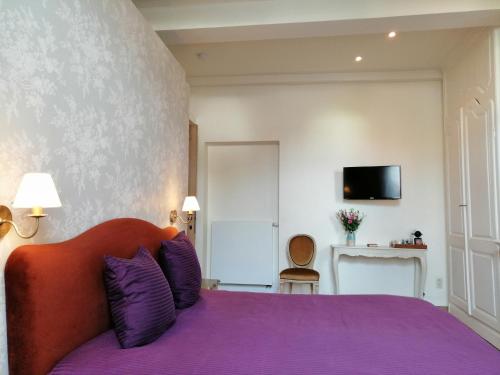 a bedroom with a purple bed with a tv on the wall at B&B Huis Willaeys in Bruges