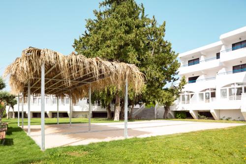 a straw umbrella in front of a building at Cyprotel Faliraki in Faliraki