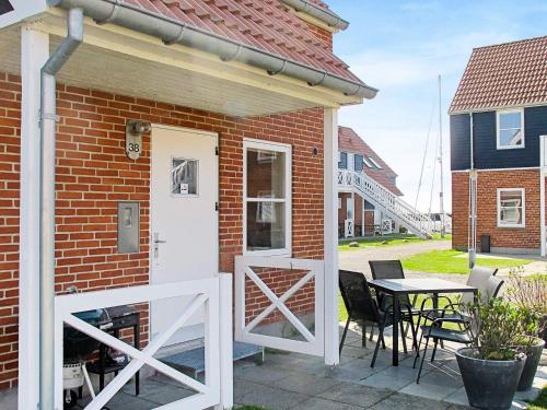ein Backsteinhaus mit einer weißen Tür und einem Tisch in der Unterkunft 4 person holiday home in Borre in Borre