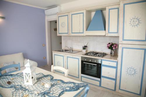 una cucina con armadi blu, tavolo e piano cottura di La Rosa Del Mare a Castelsardo