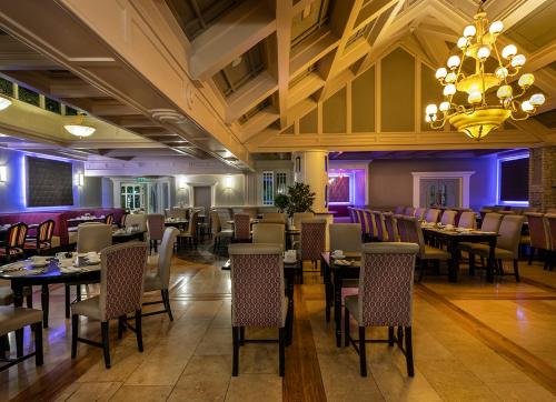 a restaurant with tables and chairs and a chandelier at Treacys Oakwood Hotel, Shannon in Shannon