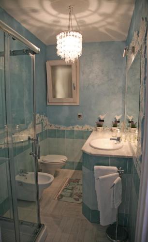 a bathroom with a sink and a toilet and a chandelier at La Rosa Del Mare in Castelsardo