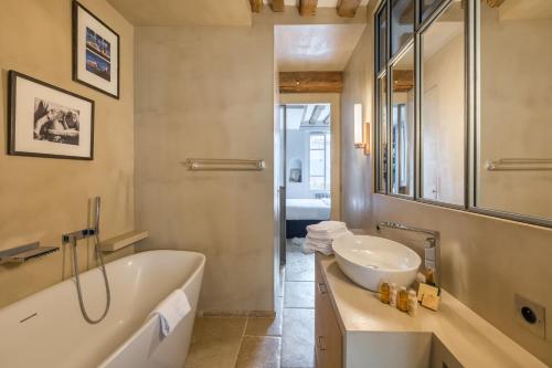 a bathroom with a tub and a sink and a mirror at Veeve - Saint-Louis Style in Paris