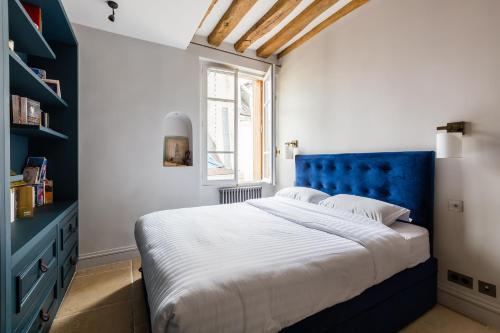 sypialnia z niebieskim łóżkiem i oknem w obiekcie Veeve - Saint-Louis Style w Paryżu