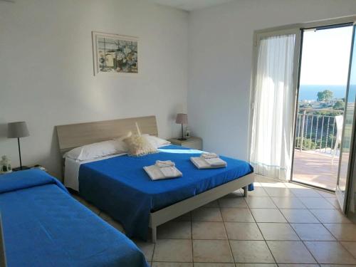 um quarto com 2 camas com lençóis azuis e uma varanda em I Cardinali em Santa Marinella