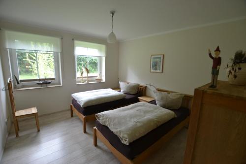 ボルンにあるFerienhaus Dineのベッド2台、椅子、窓2つが備わる客室です。