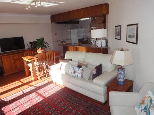 a living room with a white couch and a kitchen at Orchidea Terrace in Malveira da Serra