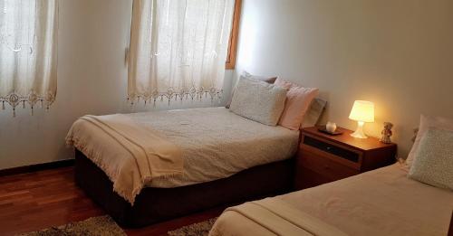 a bedroom with two beds and a lamp on a night stand at Dúplex Nigrán in Nigrán
