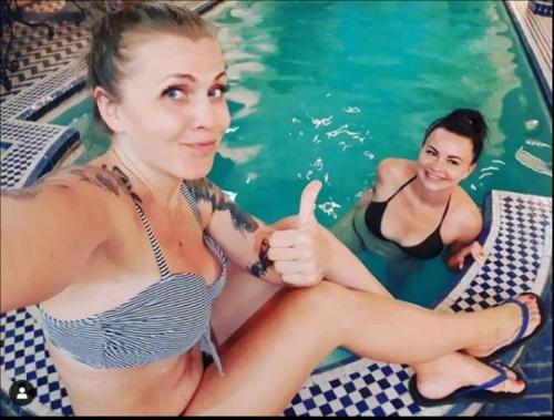 Due donne sedute in piscina che alzano i pollici di Riad Puchka a Marrakech