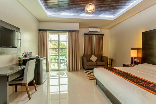 a bedroom with a bed and a desk and a chair at Aneeda Inn in Pantai Cenang