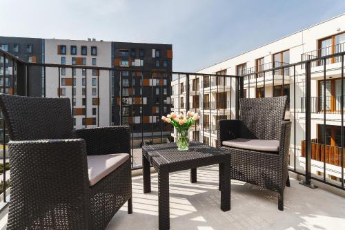 een balkon met stoelen en een tafel met een vaas met bloemen bij Apartments GO Rakowicka by Noclegi Renters in Krakau