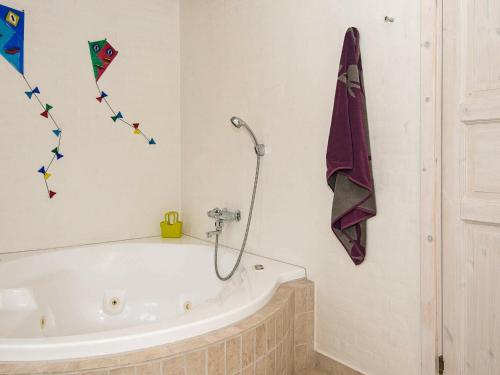 a bath tub in a bathroom with kites on the wall at 7 person holiday home in Bl vand in Blåvand