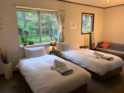 a bedroom with two beds and a window at モンブラン白馬ファミリア バケーションハウス in Hakuba