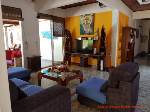 a living room with two couches and a tv at Villa Les Cocotiers in Nosy Be