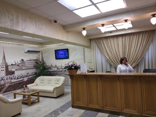 a woman standing at a reception desk in a room at Derzhavniy Hotel in Moscow
