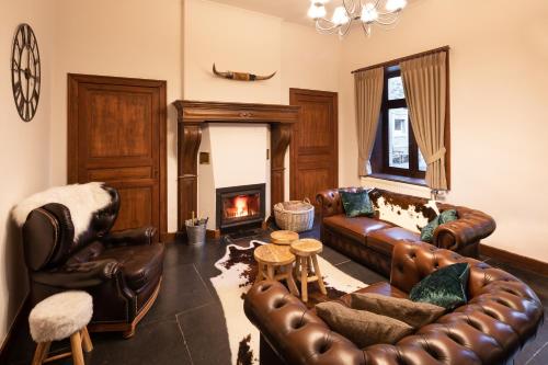 a living room with leather furniture and a fireplace at Château-ferme des Abys in Paliseul