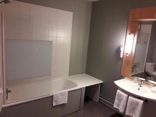 a bathroom with a bath tub and a sink at ibis Lannion in Lannion