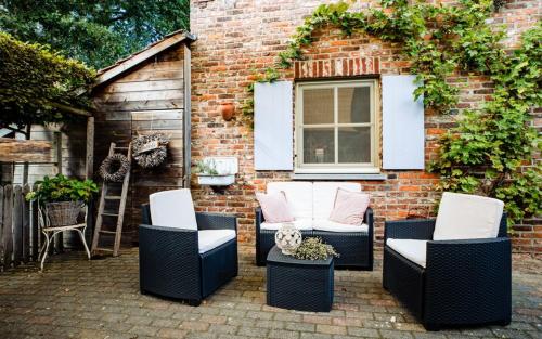 a patio with chairs and a brick building at Bij de Zöster in Kinrooi